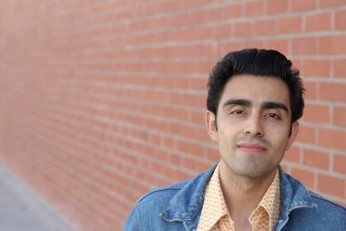 Kırmızı tuğla duvarın arka planında iyi bir adamın yakın plan portresi.