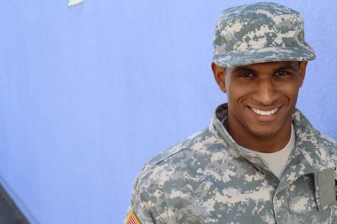 Mavi duvarın önünde üniformalı yakışıklı Afro-Amerikan askerinin yakın plan portresi