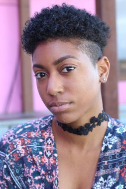 Mor duvar arkasında kısa kıvırcık saçlı güzel bir Afrikalı kadının yakın plan portresi. 