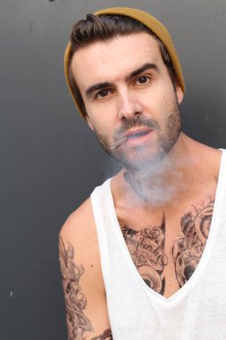 Sokakta dövmeleri olan genç ve yakışıklı bir adamın yakın plan fotoğrafı.