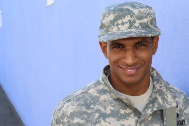 Mavi duvarın önünde üniformalı yakışıklı Afro-Amerikan askerinin yakın plan portresi