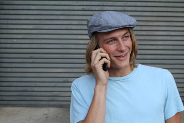 Sokakta telefonla konuşan, uzun saçlı, yakışıklı bir genç adamın yakın plan portresi.