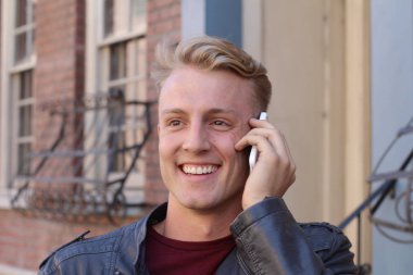 Bulanık şehir klasik arka planına sahip, telefon kullanan sarışın yakışıklı adamın yakın portresi.