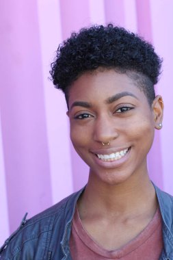 Mor duvar arkasında kısa kıvırcık saçlı güzel bir Afrikalı kadının yakın plan portresi. 