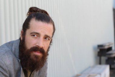 Tarz sahibi sakallı hippi modeli. Erkek saç stili, sokakta yaşam tarzı, tarlanın derinliği.