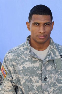 Mavi duvarın önünde üniformalı yakışıklı Afro-Amerikan askerinin yakın plan portresi