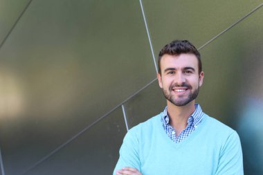 İşaretli gömlekli genç bir adam portresi ve kolları çapraz duran cyan süveter.