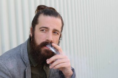 Sigara içen yakışıklı sakallı adamın portresi. Erkek saçı olan hippi..