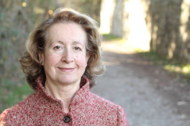 Olgun bir kadın gündüz vakti parkta duruyor.