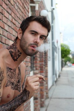 Sokakta dövmeleri olan genç ve yakışıklı bir adamın yakın plan fotoğrafı.