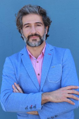 Mavi duvarın önünde pembe gömlekli yakışıklı yetişkin bir adamın yakın plan portresi.