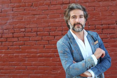 Tuğla duvarın önünde takım elbiseli yakışıklı bir iş adamının yakın plan portresi.