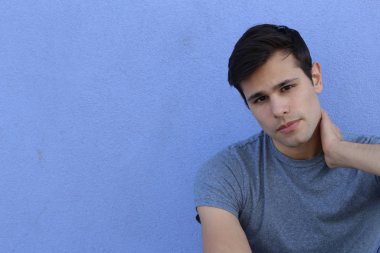 Mavi duvarın önünde sıradan giyinmiş yakışıklı bir gencin yakın plan portresi.
