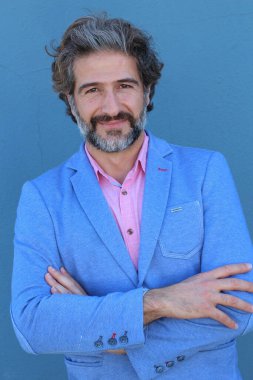 Mavi duvarın önünde pembe gömlekli yakışıklı yetişkin bir adamın yakın plan portresi.
