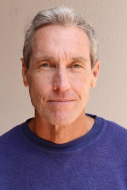 Kameraya bakan mor kazaklı yakışıklı olgun bir adamın yakın plan portresi.