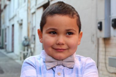 Açık havada, papyon takan şirin bir çocuğun portresi.