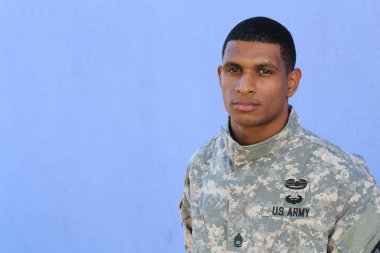 Mavi duvarın önünde üniformalı yakışıklı Afro-Amerikan askerinin yakın plan portresi