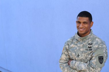 Mavi duvarın önünde üniformalı yakışıklı Afro-Amerikan askerinin yakın plan portresi
