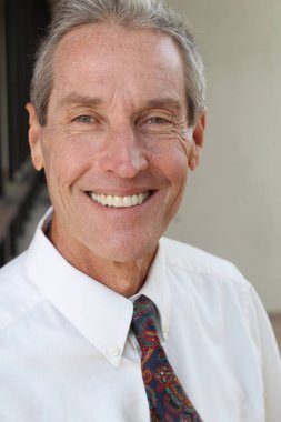 Kameraya bakan beyaz gömlekli, yakışıklı, olgun iş adamının yakın plan portresi.