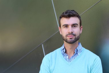 İşaretli gömlekli genç bir adam portresi ve kolları çapraz duran cyan süveter.