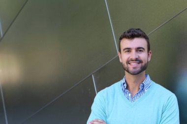 İşaretli gömlekli genç bir adam portresi ve kolları çapraz duran cyan süveter.