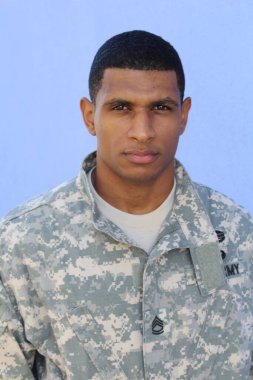 Mavi duvarın önünde üniformalı yakışıklı Afro-Amerikan askerinin yakın plan portresi