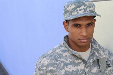 Mavi duvarın önünde üniformalı yakışıklı Afro-Amerikan askerinin yakın plan portresi