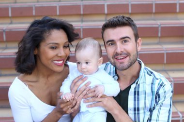 Yeni doğmuş bebeklerine sarılan ırklar arası bir çift.