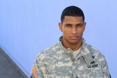 Mavi duvarın önünde üniformalı yakışıklı Afro-Amerikan askerinin yakın plan portresi