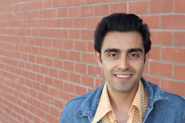 Kırmızı tuğla duvarın arka planında iyi bir adamın yakın plan portresi.