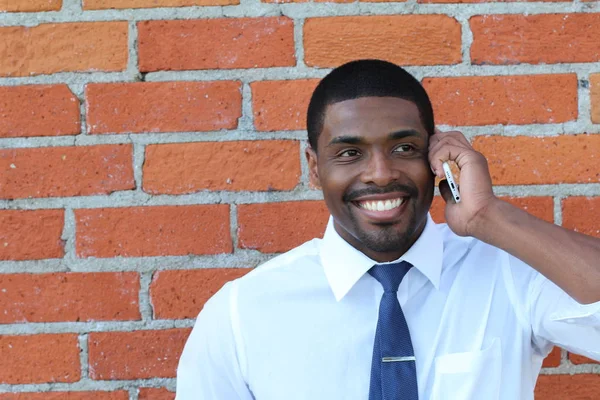 Portrait of good looking businessman or manager talking on phone, brick wall background