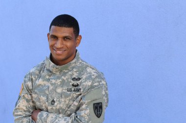Mavi duvarın önünde üniformalı yakışıklı Afro-Amerikan askerinin yakın plan portresi