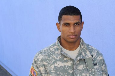 Mavi duvarın önünde üniformalı yakışıklı Afro-Amerikan askerinin yakın plan portresi