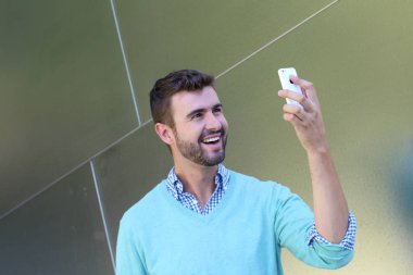 Kareli gömlekli genç bir adamın portresi ve telefonda konuşan Cyan süveteri. 