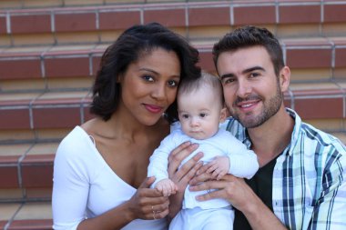 Yeni doğmuş bebeklerine sarılan ırklar arası bir çift.