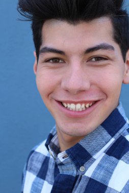 Mavi duvarın önünde poz veren yakışıklı genç adamın yakın plan portresi.