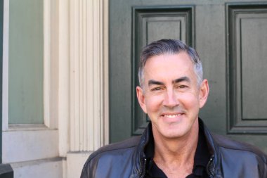 Sokakta deri ceketli yakışıklı olgun bir adamın yakın plan portresi.