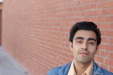 Kırmızı tuğla duvarın arka planında iyi bir adamın yakın plan portresi.