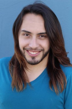 Mavi duvarın önünde uzun saçlı yakışıklı genç adamın yakın plan portresi.