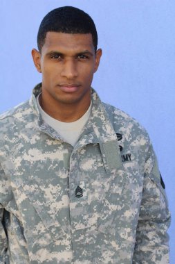 Mavi duvarın önünde üniformalı yakışıklı Afro-Amerikan askerinin yakın plan portresi