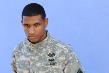 Mavi duvarın önünde üniformalı yakışıklı Afro-Amerikan askerinin yakın plan portresi