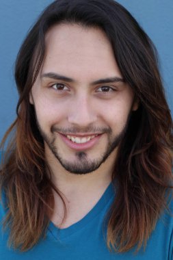 Mavi duvarın önünde uzun saçlı yakışıklı genç adamın yakın plan portresi.