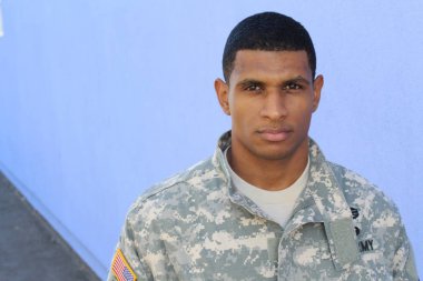 Mavi duvarın önünde üniformalı yakışıklı Afro-Amerikan askerinin yakın plan portresi