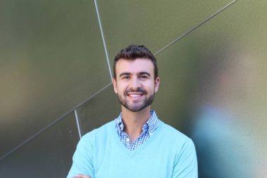 İşaretli gömlekli genç bir adam portresi ve kolları çapraz duran cyan süveter.