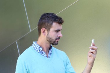 Kareli gömlekli genç bir adamın portresi ve telefonda konuşan Cyan süveteri. 