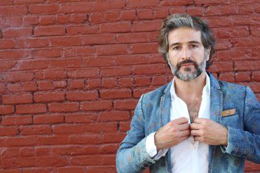 Tuğla duvarın önünde takım elbiseli yakışıklı bir iş adamının yakın plan portresi.