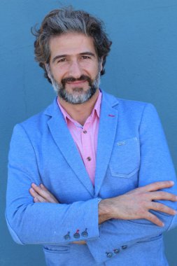 Mavi duvarın önünde pembe gömlekli yakışıklı yetişkin bir adamın yakın plan portresi.