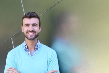 İşaretli gömlekli genç bir adam portresi ve kolları çapraz duran cyan süveter.