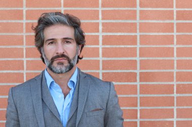 Duvarın önünde gri takım elbiseli yakışıklı bir iş adamının yakın plan portresi.