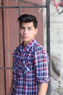 Ekose gömlekli yakışıklı genç adamın yakın plan portresi. Sokakta kameraya bakıyor.